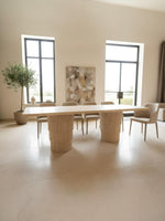 Table à manger Marrakechoise en travertin naturel, pieds striés décalés, design marocain contemporain haut de gamme.