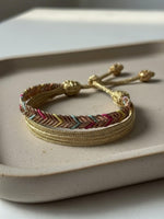 Bracelet en passementerie multicolore & or, motif chevron, fait main au Maroc. Tressage Sfifa, 50% soie / 50% fil d’or. Ruban tressé avec cordon coulissant et embouts décoratifs, dominante rose soutenu.
