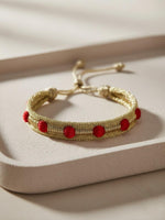 Bracelet en passementerie or et boule rouge, inspiré des cafetans marocains, fait main avec 50% fil de soie et 50% fil d'or, alliant tradition et haute couture artisanale marocaine.