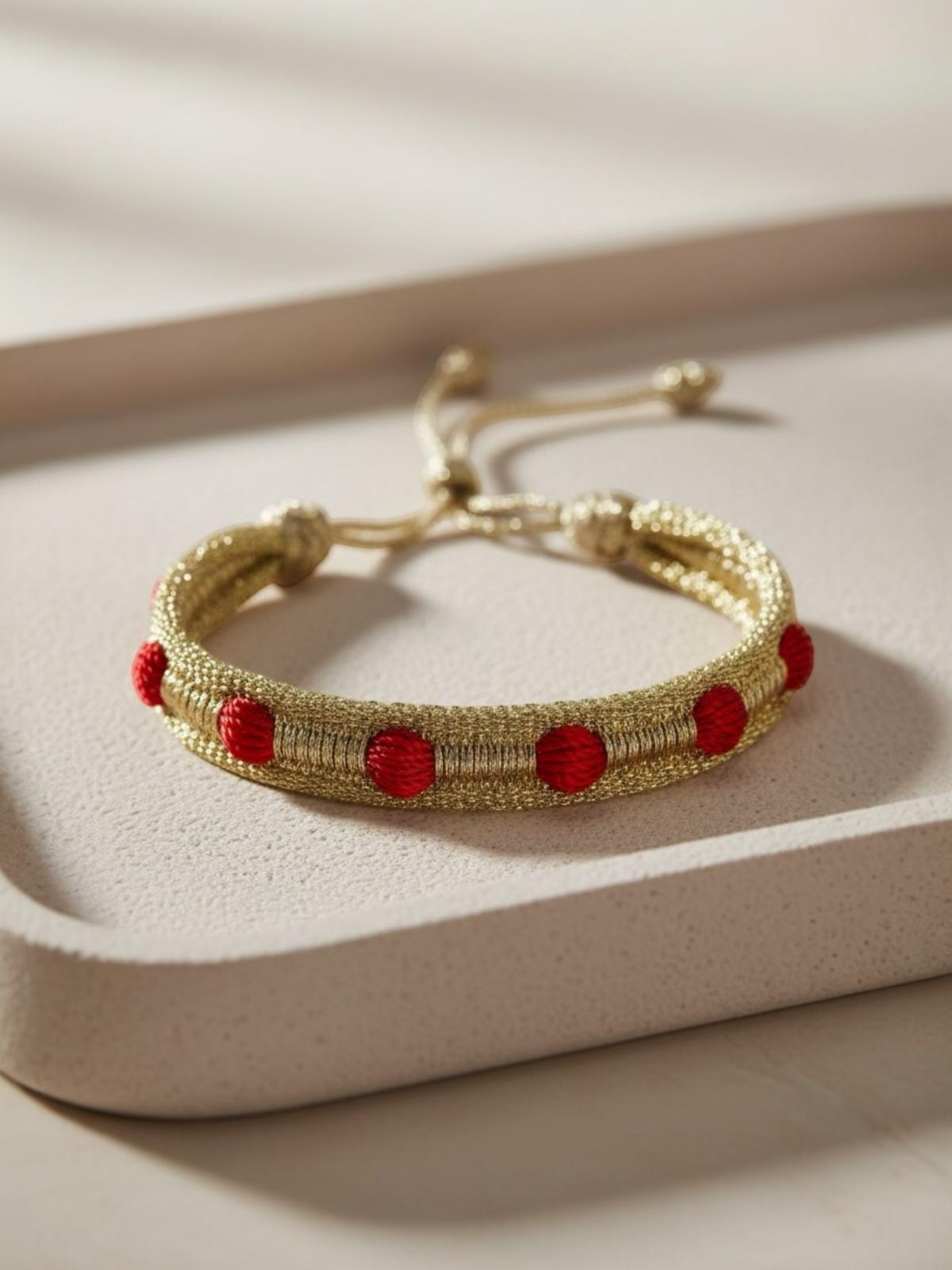 Bracelet en passementerie or et boule rouge, inspiré des cafetans marocains, fait main avec 50% fil de soie et 50% fil d'or, alliant tradition et haute couture artisanale marocaine.