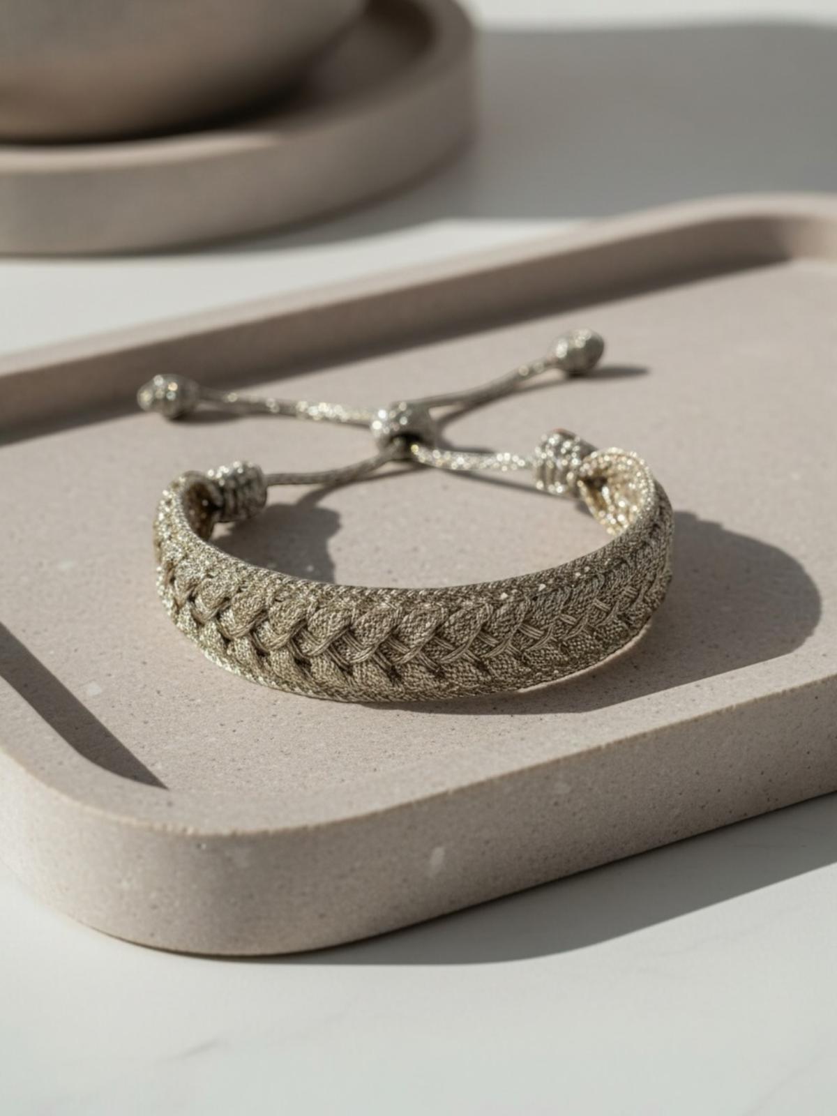 Bracelet en passementerie tressée couleur or, technique Sfifa, 100% fil à effet or, fait main au Maroc, avec cordons coulissants et embouts décoratifs, posé sur plateau.